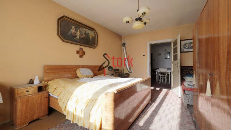 Menší rodinný dom len pár metrov od centra mesta Rajec - Spálňa v rodinnom dome s dreveným nábytkom, obrazom a lustrom.