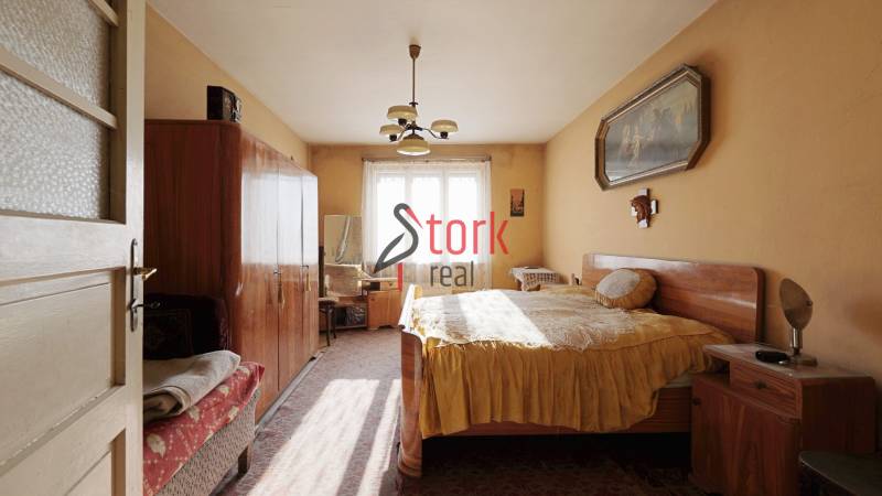 Menší rodinný dom len pár metrov od centra mesta Rajec - Spálňa v rodinnom dome s nábytkom, lusterom a obrazom na stene.