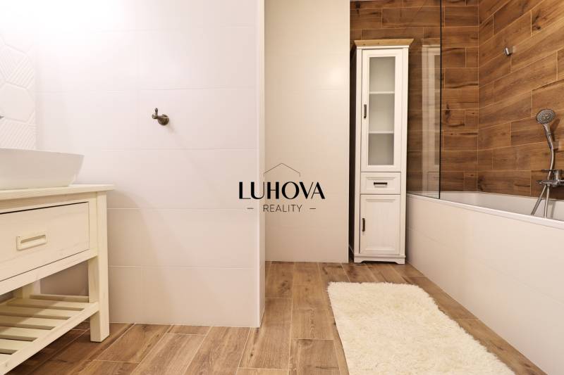 Na PRENÁJOM_ NÁDHERNÝ 3-izbový byt  - Kúpeľňa s bielymi obkladmi a podlahou s dreveným dekorom v 3-izbovom byte.