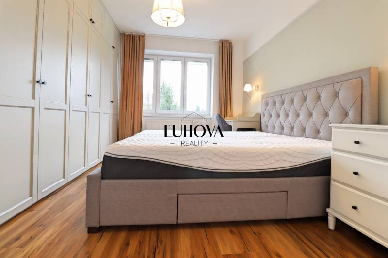 Na PRENÁJOM_ NÁDHERNÝ 3-izbový byt  - Svetlá spálňa s veľkou posteľou, vstavanou skriňou a podlahou s dreveným dekorom v 3-izbovom byte.