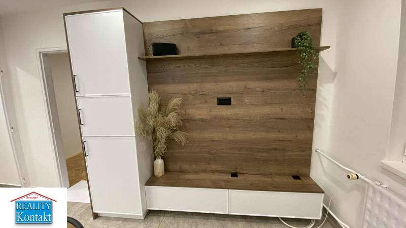 Na prenájom 1-izbový byt - Nové Zámky - V 1-izbovom byte je šatníková stena s dreveným dekorom a kvetmi vo váze.