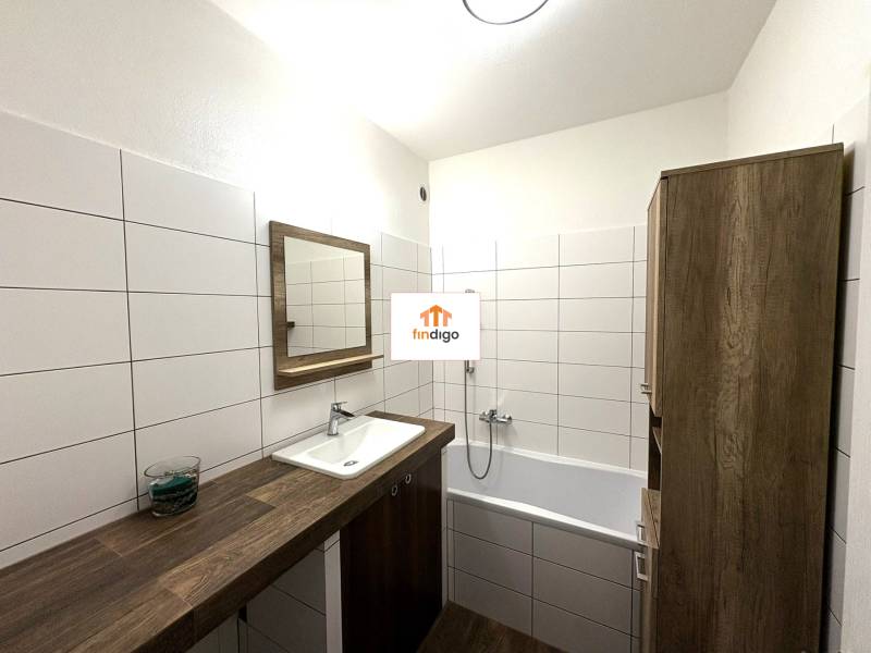 PREDAJ-  2 izbový byt neďaleko Nitry v obci Jarok - Kúpeľňa 2-izbového bytu so svetlými obkladačkami, vaňou a dreveným nábytkom.