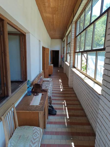 Na predaj  dom v obci Vyhne iba 400m od Vodného raja.  - Presvetlená zimná záhrada s dlažbou v rodinnom dome na ulici Vyhne, drevená lavica.