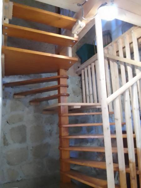 Štýlový rekreačný domček Levice - Interiér chaty so schodiskom z dreva a kamennými stenami.