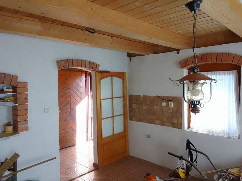 Štýlový rekreačný domček Levice - Interiér chaty s tehlovými ozdobami, podlahou s dreveným dekorom a visiacim svietidlom.