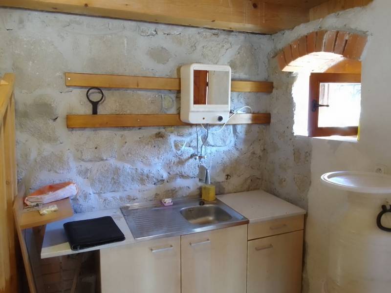 Štýlový rekreačný domček Levice - Vidiecka kuchynka v chate s kamennými stenami a drevenými detailmi.