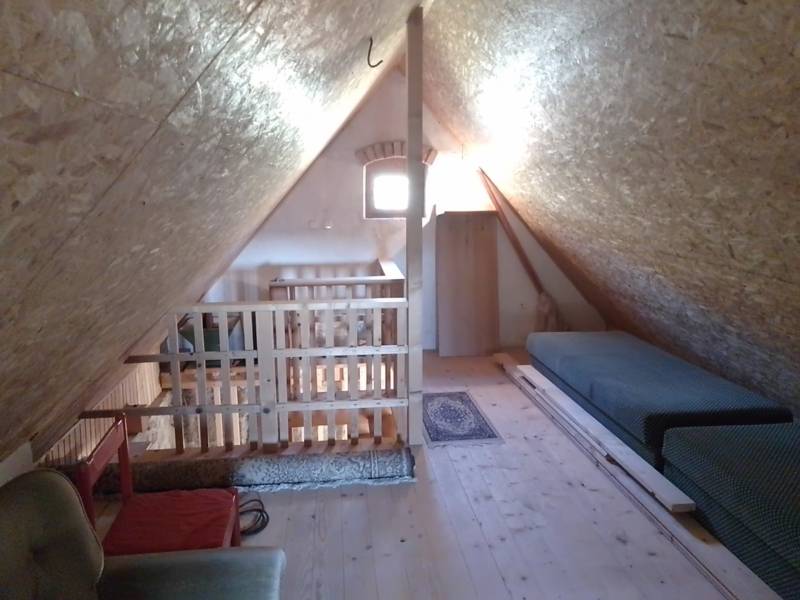 Štýlový rekreačný domček Levice - Podkrovný priestor chaty s dreveným dekorom, dvoma matracmi a kreslom.