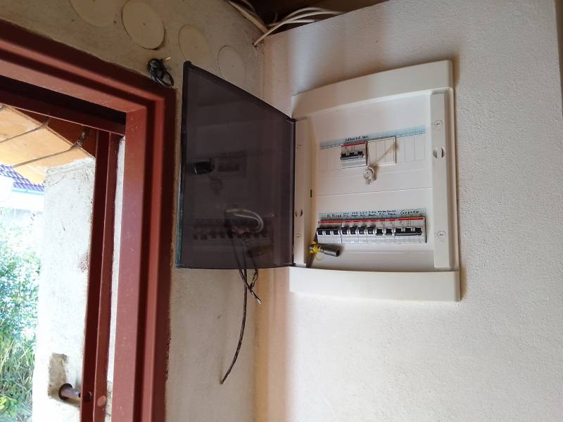 Štýlový rekreačný domček Levice - Otvorená rozvodná skriňa s ističmi v Chate, vedľa otvorených dverí.