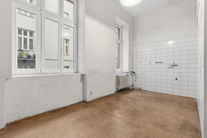 3- izb. byt o výmere 105m2 v historickom centre. - Prázdna miestnosť v 3-izbovom byte s oknami a radiátorom, dlaždičky na stene.