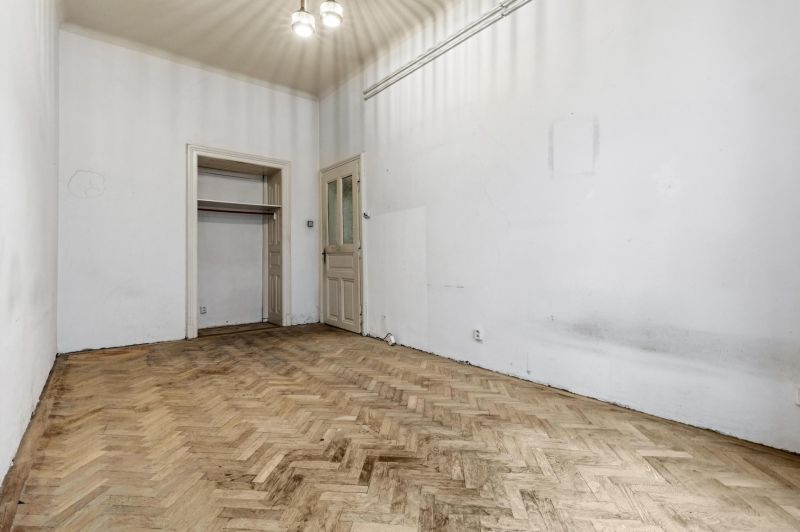 3- izb. byt o výmere 105m2 v historickom centre. - Prázdna miestnosť v 3-izbovom byte s podlahou s dreveným dekorom a bielymi stenami.