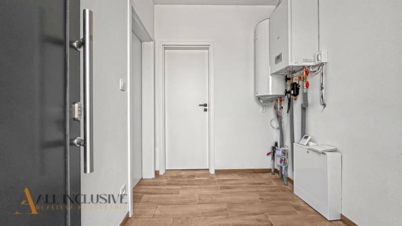 IDEÁLNY 1 IZBOVÝ BYT | VEĽKÉ RIPŇANY | TOPOĽČANY - Vstupná chodba v 1-izbovom byte s bielymi stenami a podlahou s dreveným dekorom.