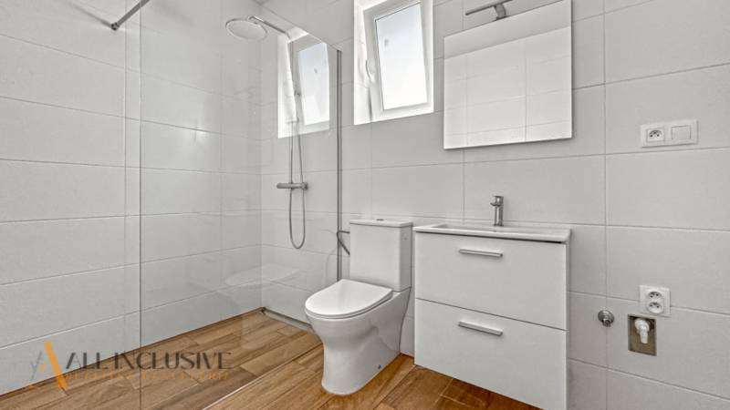 IDEÁLNY 1 IZBOVÝ BYT | VEĽKÉ RIPŇANY | TOPOĽČANY - Kúpeľňa s podlahou s dreveným dekorom v 1-izbovom byte.