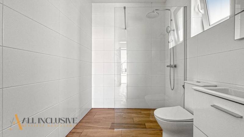 IDEÁLNY 1 IZBOVÝ BYT | VEĽKÉ RIPŇANY | TOPOĽČANY - Kúpeľňa v 1-izbovom byte s elegantnou podlahou s dreveným dekorom a sklenenou sprchovou stenou.