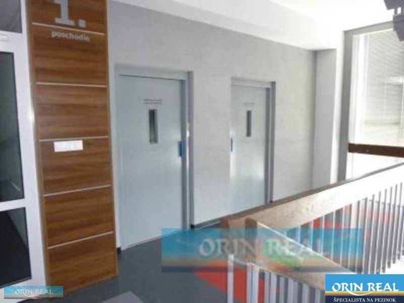 PRENÁJOM KANCELÁRSKÝCH PRIESTOROV NA RAČIANSKEJ ULICI - Priestor na prvom poschodí s dvomi šedými dverami a hnedým obložením.