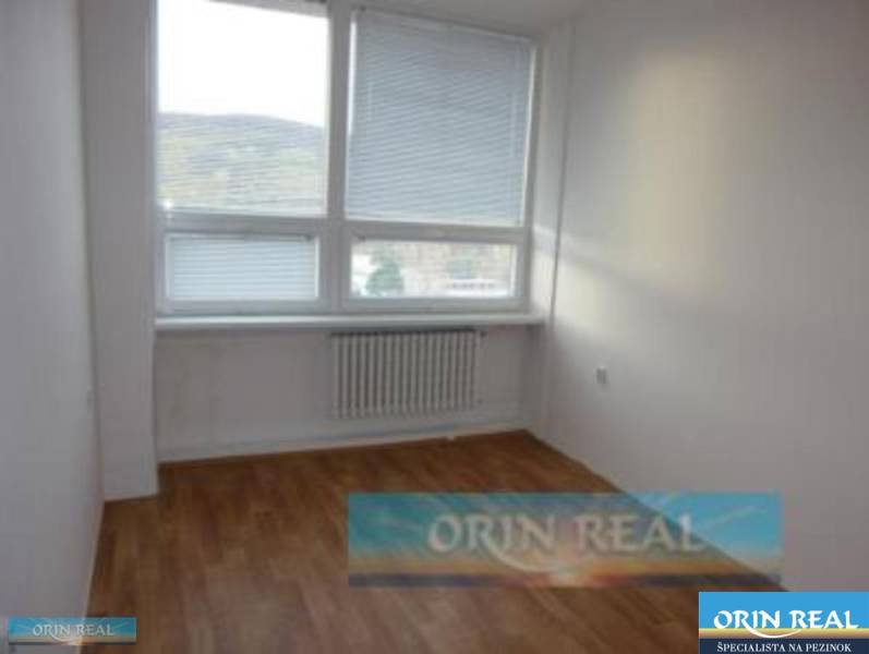 PRENÁJOM KANCELÁRSKÝCH PRIESTOROV NA RAČIANSKEJ ULICI - Izba s drevenou podlahou a veľkým oknom, ideálny priestor na kancelárie na ulici Račianska.