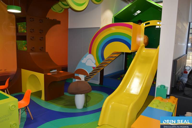 PRENÁJOM NEB.PRIESTORU V POLYFUNKČNOM DOME V CENTRE PEZINKA - Hravé detské ihrisko s dúhovou šmykľavkou a farebným nábytkom, vhodné obchodné priestory.
