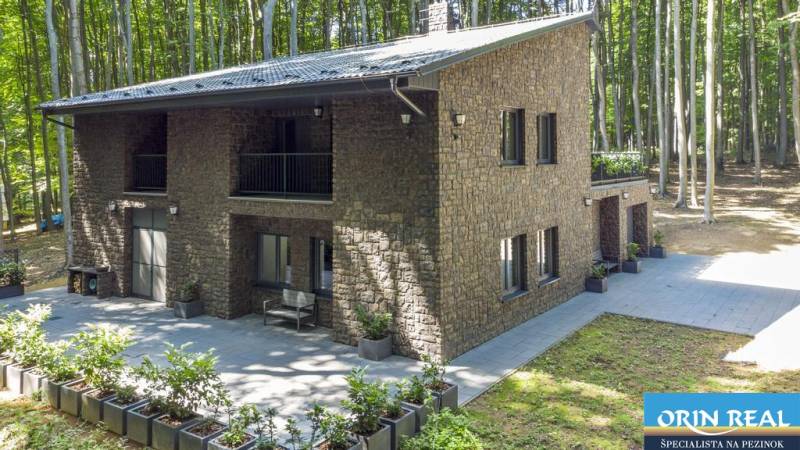 PREDAJ 8 IZB.REKREAČNEJ CHATY - VILY V MODRE HARMÓNII - Dom s kamennou fasádou a terasou pri lese, blízko ulice Piesok a chaty.
