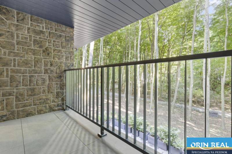 PREDAJ 8 IZB.REKREAČNEJ CHATY - VILY V MODRE HARMÓNII - Balkón s kamennou stenou ponúka výhľad na les pri Chate na ulici Piesok.