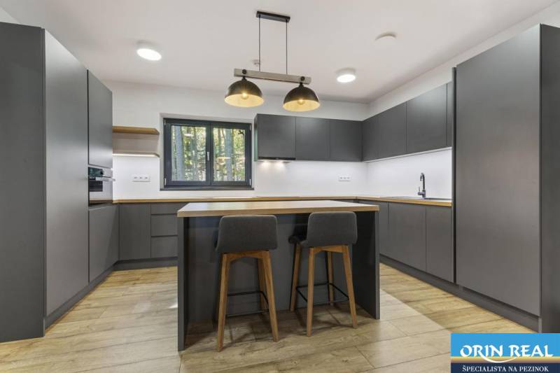 PREDAJ 8 IZB.REKREAČNEJ CHATY - VILY V MODRE HARMÓNII - Kuchyňa s tmavými skrinkami, drevenou podlahou, barovými stoličkami, na ulici Piesok.