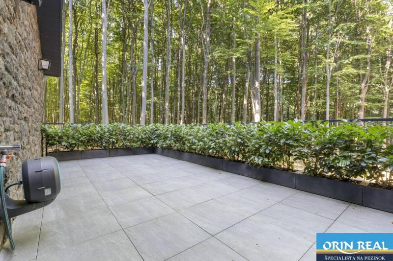 PREDAJ 8 IZB.REKREAČNEJ CHATY - VILY V MODRE HARMÓNII - Terasa s výhľadom na les, lemovaná zelenými kríkmi, na ulici Piesok a Chata.