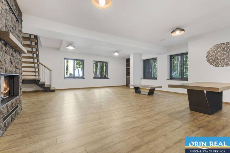 PREDAJ 8 IZB.REKREAČNEJ CHATY - VILY V MODRE HARMÓNII - Obývacia izba s drevenou podlahou, krbom, schodiskom a veľkými oknami na ulici Piesok.