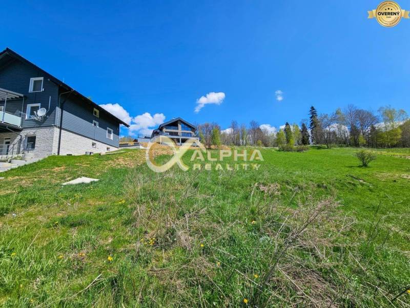 Stavebný pozemok lokalita Slnečná úboč, Levočská Dolina, okres Levoča - Trávnatá plocha a domy v Levoči, pozemky - bývanie obklopené prírodou a stromami.