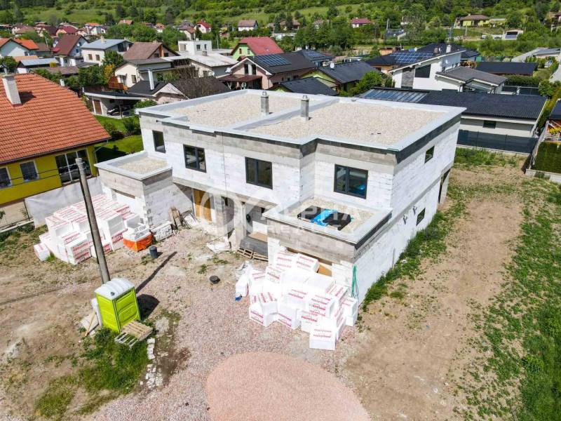 Exkluzívne na predaj, rodinný dom, obec Harichovce, okres Spišská Nová - Stavba rodinného domu v Harichovciach so stavebnými materiálmi a susednými domami v pozadí.