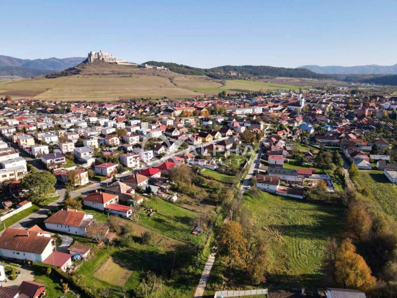 EXKLUZÍVNE stavebné pozemky, Spišské Podhradie - Letecký pohľad na pozemky na bývanie v Spišskom Podhradí s hradom v pozadí.