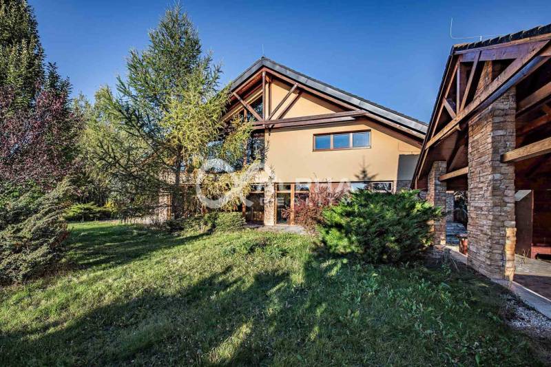 Exkluzívny rodinný dom, Veľká Lomnica, okres Kežmarok - Rodinný dom vo Veľkej Lomnici s trávnatou záhradou, obklopený stromami a kamenitou fasádou.