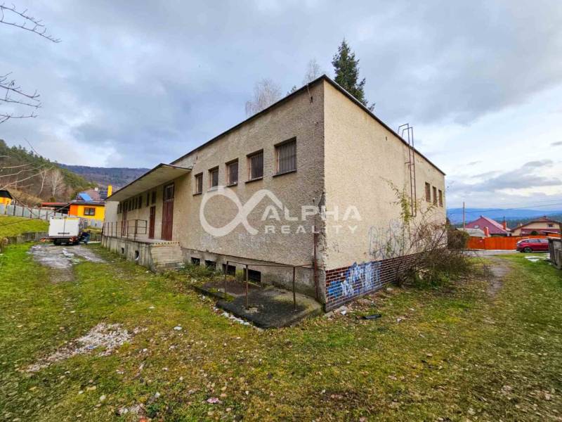 Budova s pozemkom, obec Helcmanovce, okres Gelnica - Budova v Helcmanovciach s trávnatým okolím a susednými domami, obklopená kopcami.