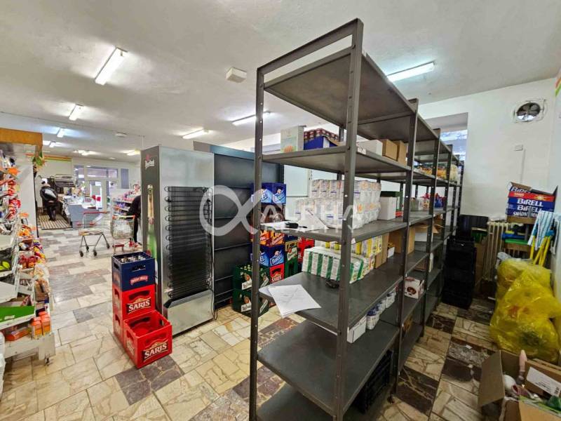 Budova s pozemkom, obec Helcmanovce, okres Gelnica - Predajňa s regálmi a tovarom, podlaha s dreveným dekorom, interiér budovy.