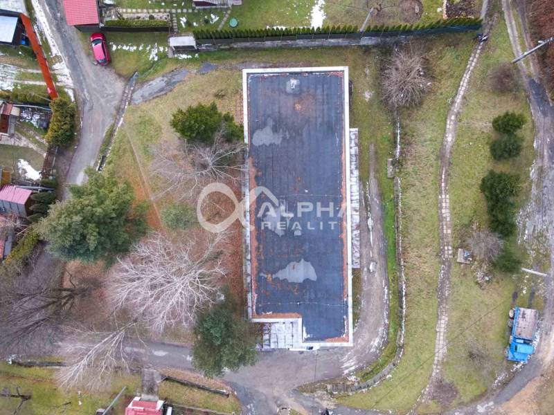 Budova s pozemkom, obec Helcmanovce, okres Gelnica - Letecký pohľad na budovu v Helcmanovciach obklopenú stromami a príjazdovými cestami.