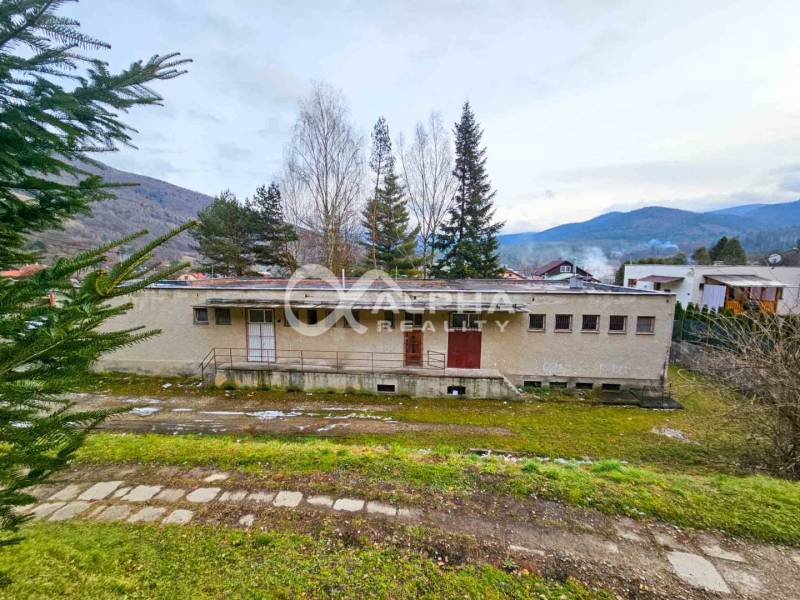 Budova s pozemkom, obec Helcmanovce, okres Gelnica - Budova v Helcmanovciach obklopená prírodou s kopcami v pozadí.