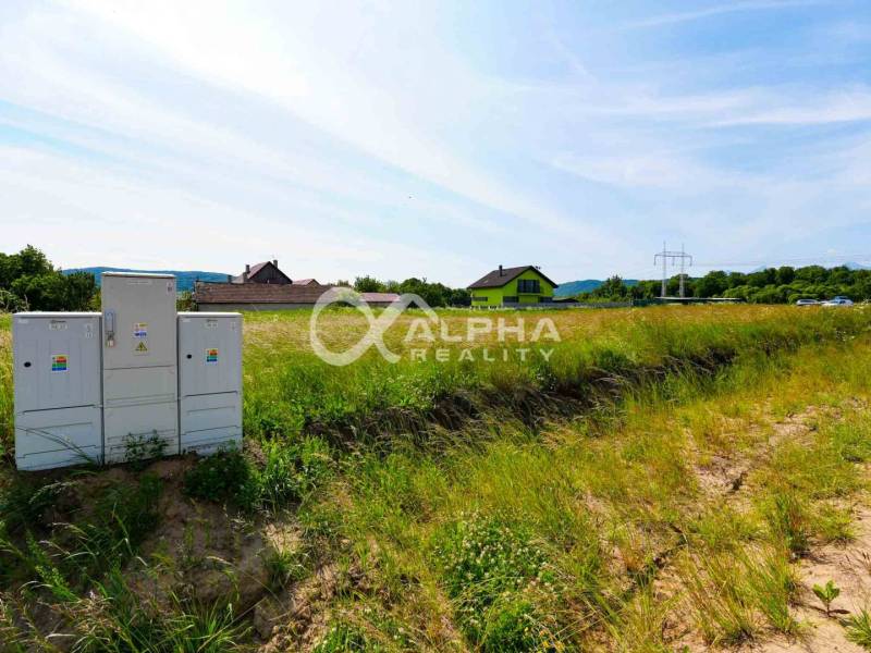 Pozemok 992m2, obec Betlanovce, okres Sp.N.Ves - Pozemky - bývanie v Betlanovciach so zeleňou, domami a elektrickými skriňami na pozadí.