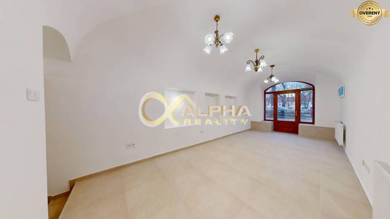 Polyfunkčný priestor na predaj, Zimná ul., Spišská Nová Ves - Obchodné priestory s oblúkovými dverami a podlahou s dreveným dekorom, biele steny, luster.