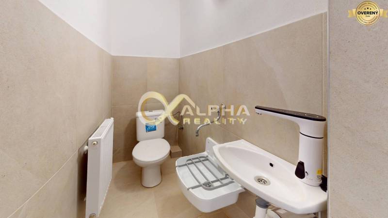 Polyfunkčný priestor na predaj, Zimná ul., Spišská Nová Ves - Kúpeľňa so záchodom, bielym umývadlom a nástenným radiátorom v obchodných priestoroch.