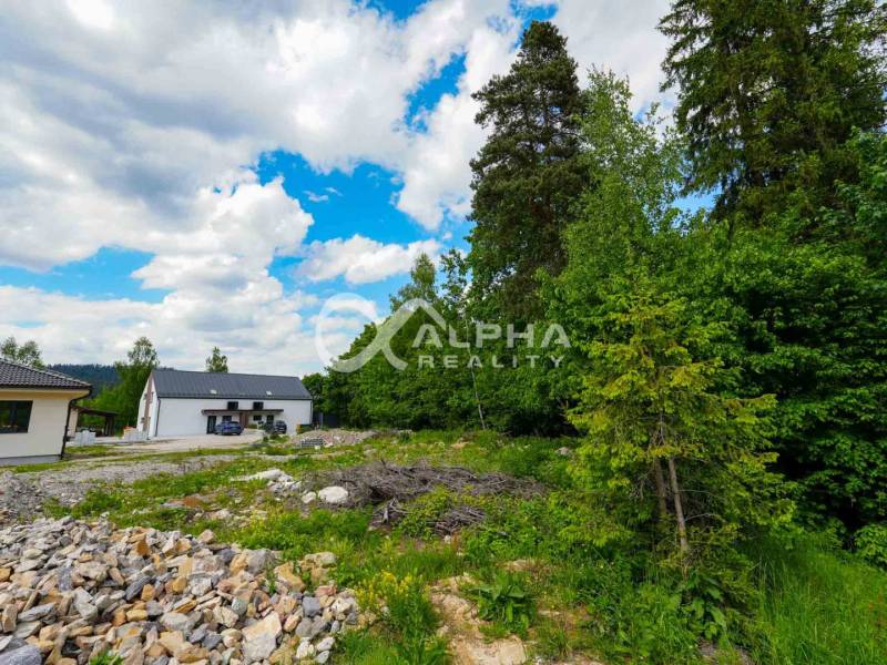 EXKLUZÍVNE Stavebný pozemok, 916m2, Novoveská Huta - Pozemok na bývanie v Spišskej Novej Vsi, okolité domy, les a modrá obloha.