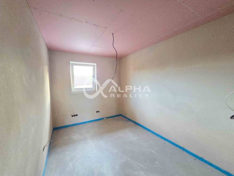 Rodinné domy, obec Danišovce, okr. Spišská Nová Ves - Prázdna miestnosť s oknom, omietnutými stenami a betónovou podlahou v rodinnom dome.