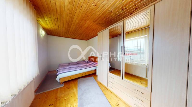 EXKLUZÍVNE Rodinný dom, širšie centrum, Spišská Nová Ves - Spálňa s podlahou s dreveným dekorom, vstavanou skriňou a posteľou v rodinnom dome.