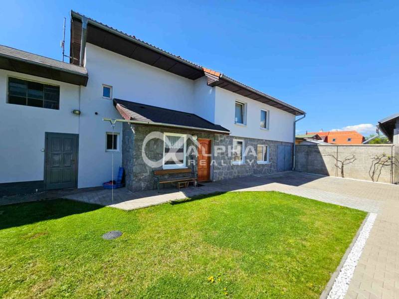 EXKLUZÍVNE Rodinný dom, širšie centrum, Spišská Nová Ves - Rodinný dom v Spišskej Novej Vsi s upraveným trávnikom, kamennými detailmi a dláždeným chodníkom.