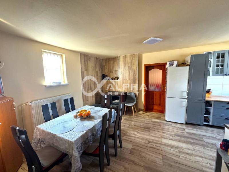 EXKLUZÍVNE Rodinný dom, širšie centrum, Spišská Nová Ves - Jedáleň rodinného domu so stolom, stoličkami a kuchynskou časťou; podlaha s dreveným dekorom.