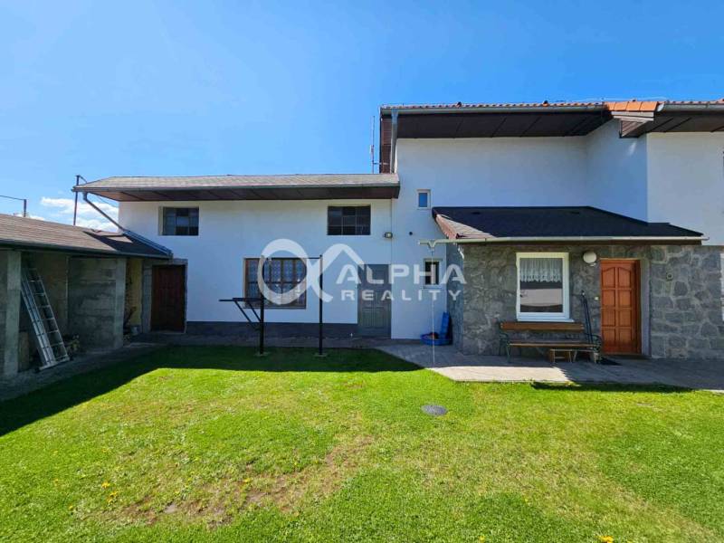 EXKLUZÍVNE Rodinný dom, širšie centrum, Spišská Nová Ves - Rodinný dom v Spišskej Novej Vsi s trávnatým dvorom, kamennými obkladmi a bielou fasádou.