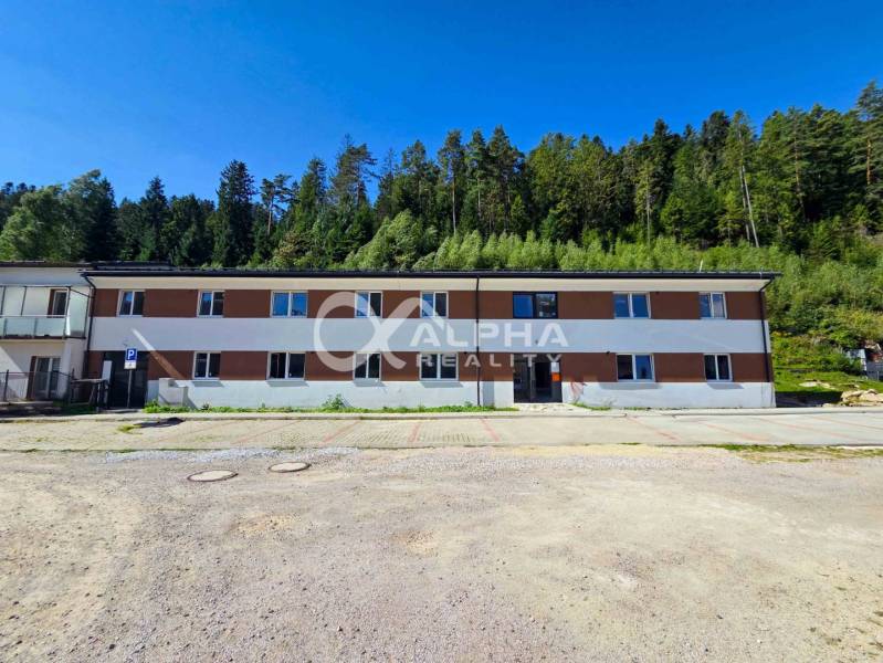 EXKLUZÍVNE novostavby bytov s terasou, parkovaním, Novoveská Huta, okr - Budova v Spišskej Novej Vsi pri lese, súčasť 3-izbového bytu, parkovisko v popredí.