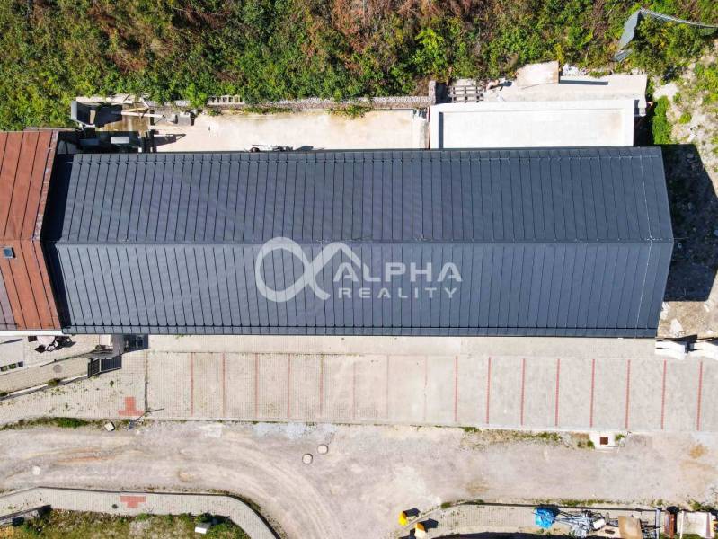 EXKLUZÍVNE novostavby bytov s terasou, parkovaním, Novoveská Huta, okr - Pohľad zhora na dlhú budovu so strechou, parkovanie a okolitú zeleň v Spišskej Novej Vsi.