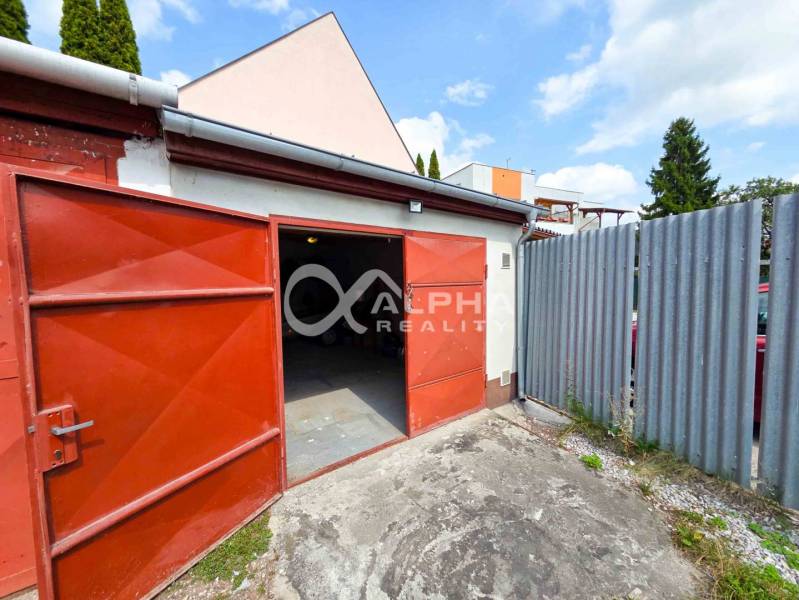 Prenájom garáž, centrum, Spišská Nová Ves - Otvorené garáže v Spišskej Novej Vsi s červenými dverami a plechovým plotom.