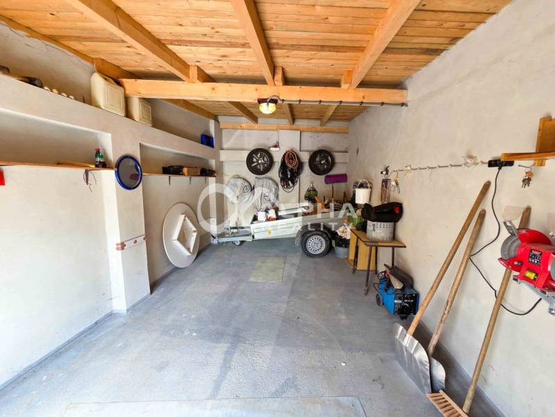 Prenájom garáž, centrum, Spišská Nová Ves - Garáže v Spišskej Novej Vsi s prívesným vozíkom, policami a náradím na stene.