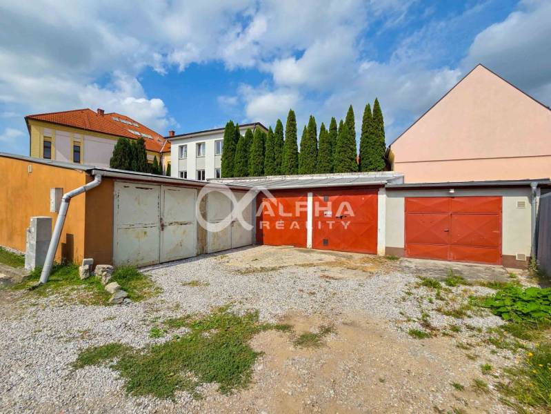 Prenájom garáž, centrum, Spišská Nová Ves - Garáže v Spišskej Novej Vsi, štrková príjazdová cesta, budovy v pozadí, cyprusy.