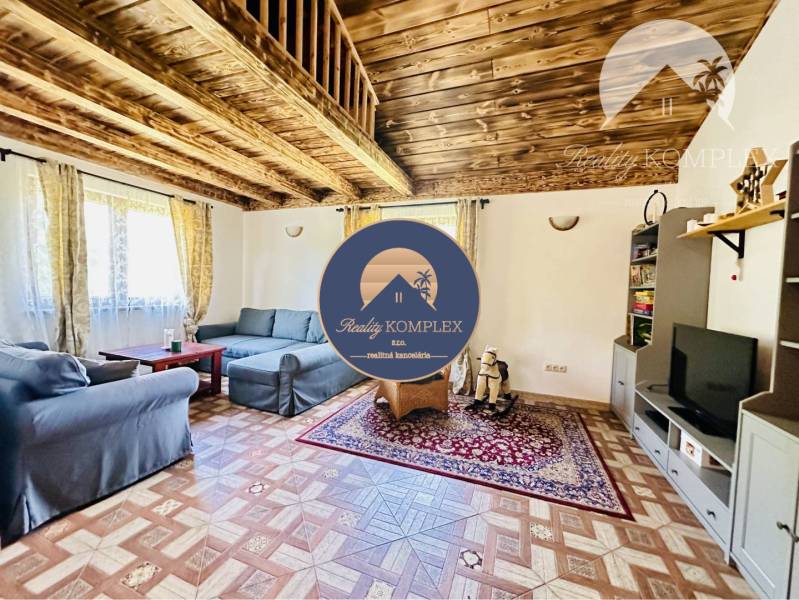 Vám ponúka na predaj rodinný dom v Komárne, ča - Obývačka v rodinnom dome s podlahou s dreveným dekorom, pohovkami a televíziou.