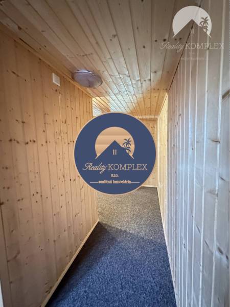 Vám ponúka na predaj rodinný dom v Komárne, ča - Drevené obloženie stien a stropu v chodbe rodinného domu s kobercom na podlahe.