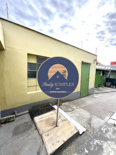 IBA U NÁS !!! ponúka EXKLUZÍVNE na predaj rodin - Exteriér rodinného domu v Komárne so žltou stenou a zelenými dverami.